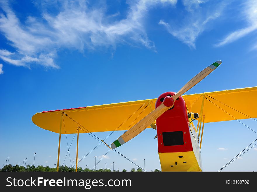 Propeller biplane from below against blue sky