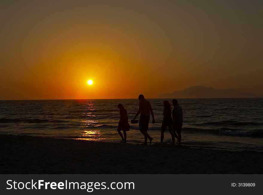 People walking on the beach at sunset. People walking on the beach at sunset