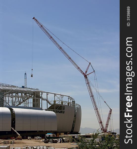 A large crane lifts people to the roof of a stadium under construction. A large crane lifts people to the roof of a stadium under construction.