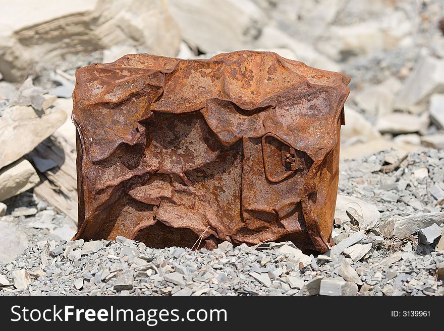 Rusted and crumpled barrel on the rocks