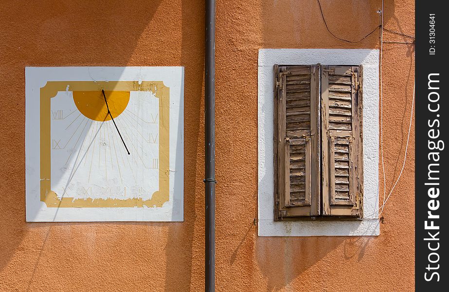 A sundial and a window on a red wall. A sundial and a window on a red wall