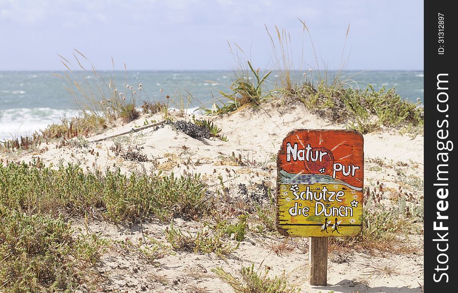 Nature is pure. Protect the dunes. (or Nature pur. Schütze die dunen) - Wooden sign, for german tourists, on a dune beach in Peniche, Portugal. Peniche is one of the best surfing locations in Europe. It has beaches and breaks facing in 3 distinctly different directions. Recently it has become one of the destination for the WCT of the ASP or World championship tour of Association of surfing professionals.