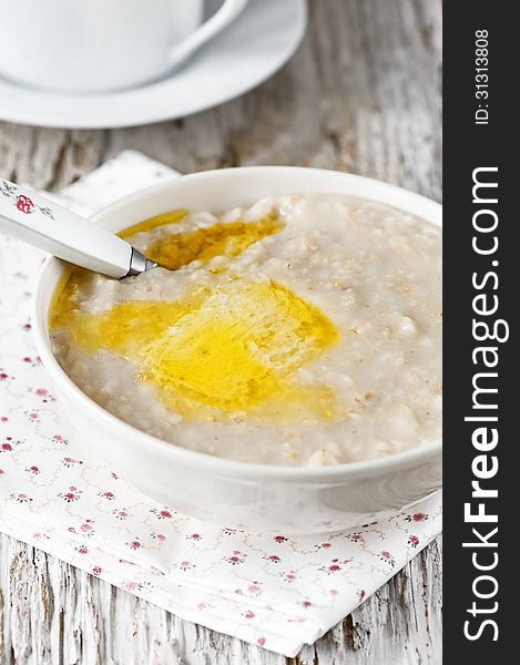 A bowl of hot oatmeal with butter on the old wooden background. A bowl of hot oatmeal with butter on the old wooden background