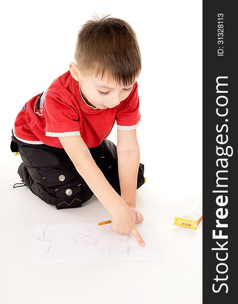 A little boy draws on the paper on white background