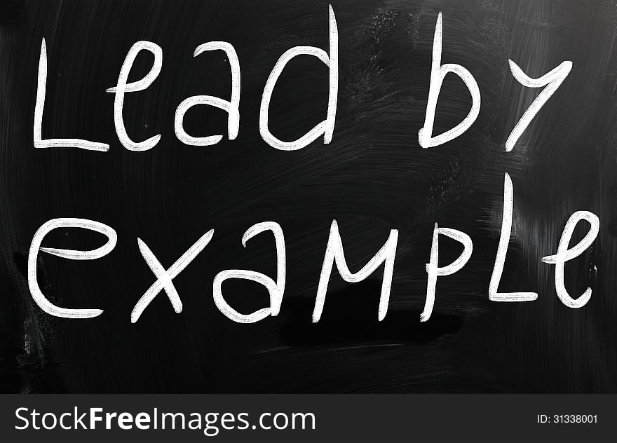 Lead by example handwritten with white chalk on a blackboard.