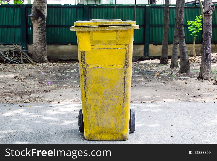 Old yellow recycling bin on concrete