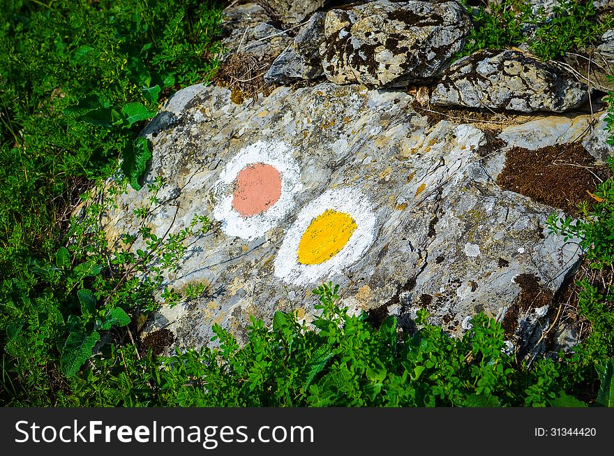 Yellow and red trail sign painted on a mountain rock. Yellow and red trail sign painted on a mountain rock