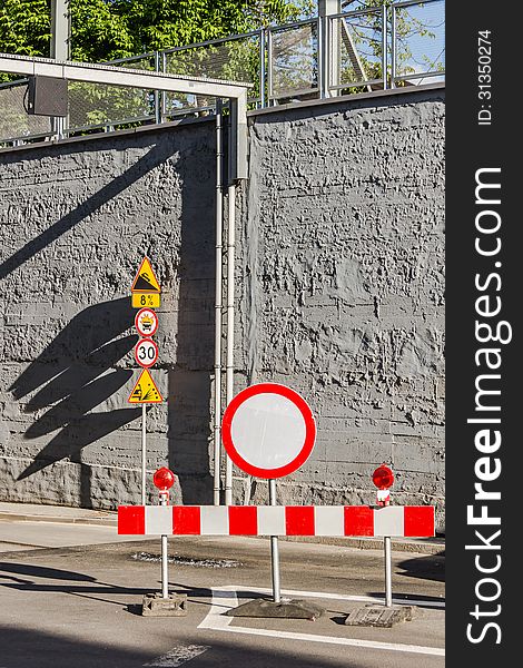 Road signs against a grey wall.