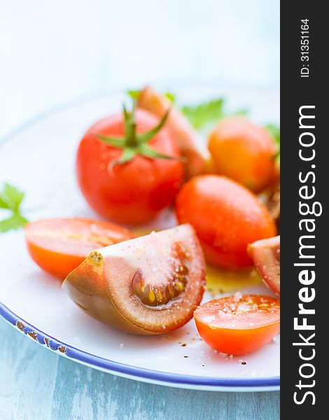 Plate with assorted tomatoes with focus to a quartered sliced tomato in the foreground