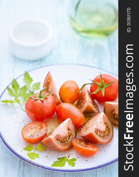 Three varieties of sliced and quartered tomato on a plate including grape tomatoes and cherry tomatoes. Three varieties of sliced and quartered tomato on a plate including grape tomatoes and cherry tomatoes