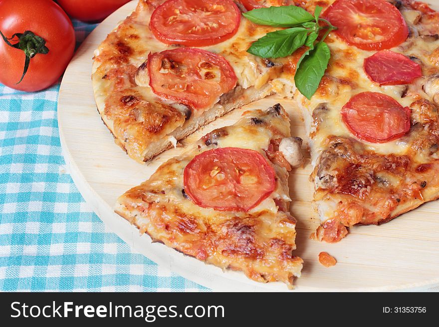 Homemade vegetarian pizza with cheese, tomatoes and mushrooms on a wooden board
