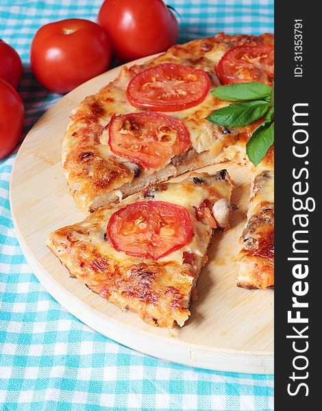 Tasty vegetarian pizza with cheese, tomatoes and mushrooms on a wooden board. Tasty vegetarian pizza with cheese, tomatoes and mushrooms on a wooden board