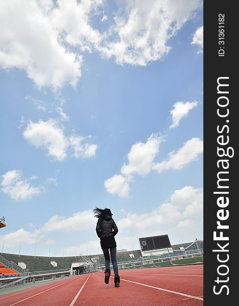 Back portrait of single young girl running in stadium