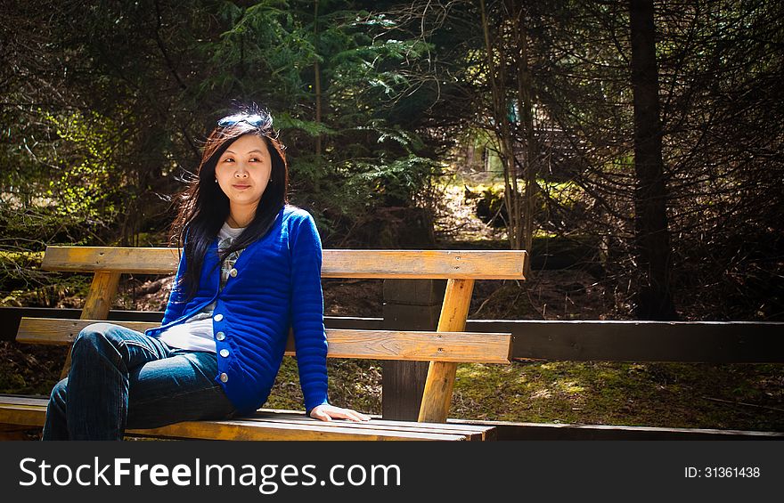 Portrait of single beautiful young girl looking aside when sitting on outdoor bench. Portrait of single beautiful young girl looking aside when sitting on outdoor bench
