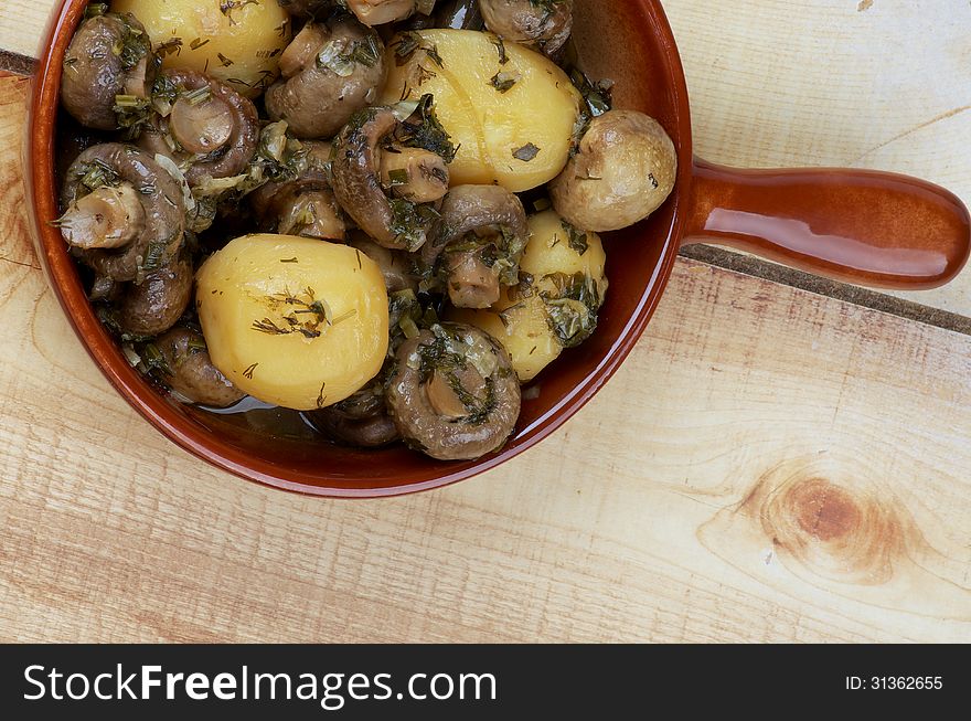 Delicious Stew with Champignon Mushrooms, Roasted Potato, Greens and Onion in Brown Frying Pan on Wood background. Top View. Delicious Stew with Champignon Mushrooms, Roasted Potato, Greens and Onion in Brown Frying Pan on Wood background. Top View