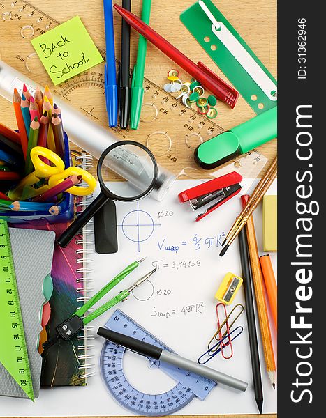 School Supplies with Note Pads, Pencils, Pens, Colored Pencils, Scissors, Pencil Sharpener, Buttons, Drawing Compass, Magnifier, Stapler, Slide-Rule and Ruler Lines on School Desk . Top View