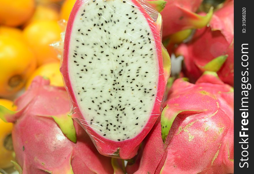 Closeup image of a fresh sliced tropical Pattaya fruit. The half fruit is wrapped for selling in a store. Closeup image of a fresh sliced tropical Pattaya fruit. The half fruit is wrapped for selling in a store.