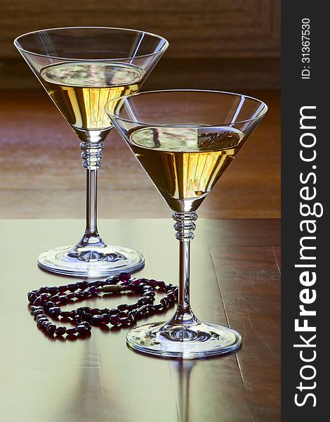 Garnet necklace and two glasses with white wine on an old table. Garnet necklace and two glasses with white wine on an old table