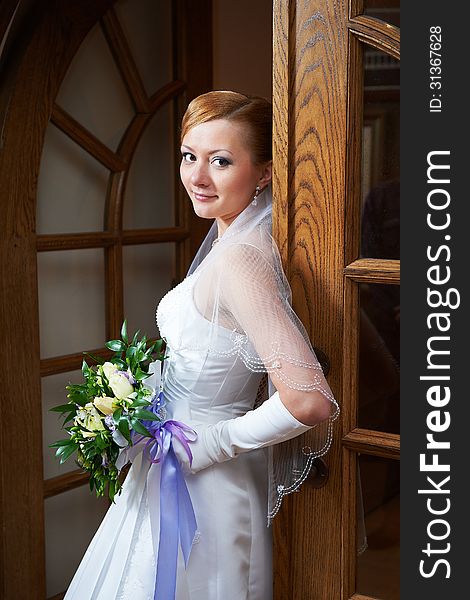 Happy beautiful bride in wedding dress near doors. Happy beautiful bride in wedding dress near doors