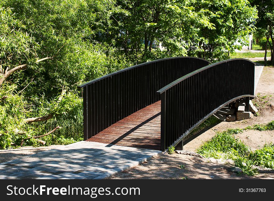 Pedestrian bridge in city park on sunny summer day