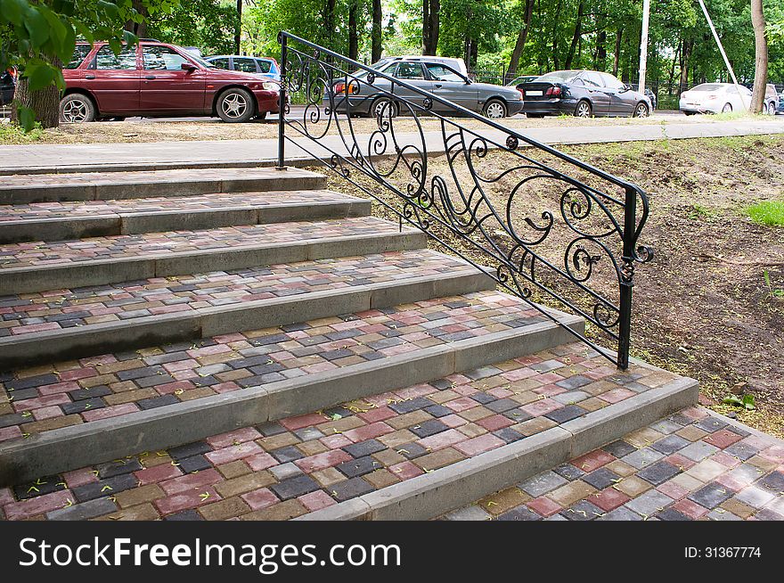 Staircase with steps of paving slabs with metal railing
