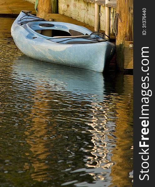 A blue canoe sits tied to a dock.