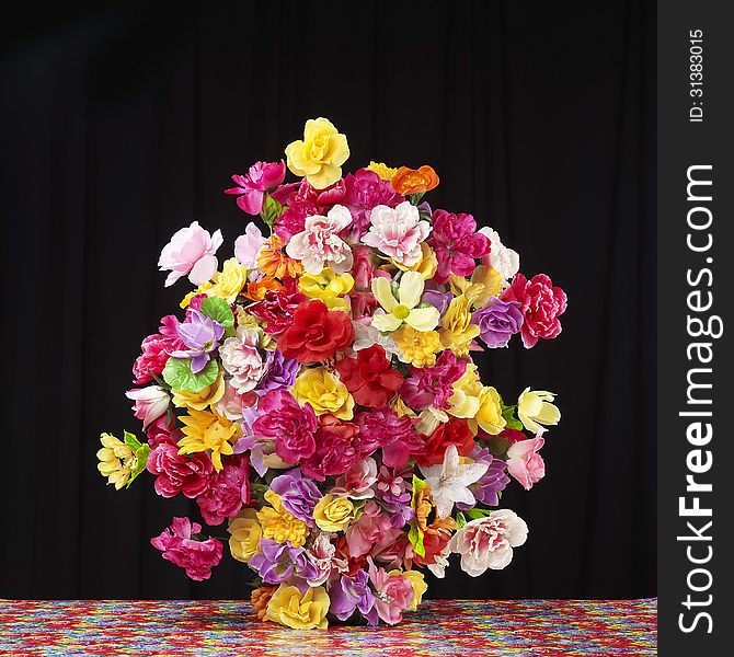A large bouquet of fake flowers sits against a black background. A large bouquet of fake flowers sits against a black background.