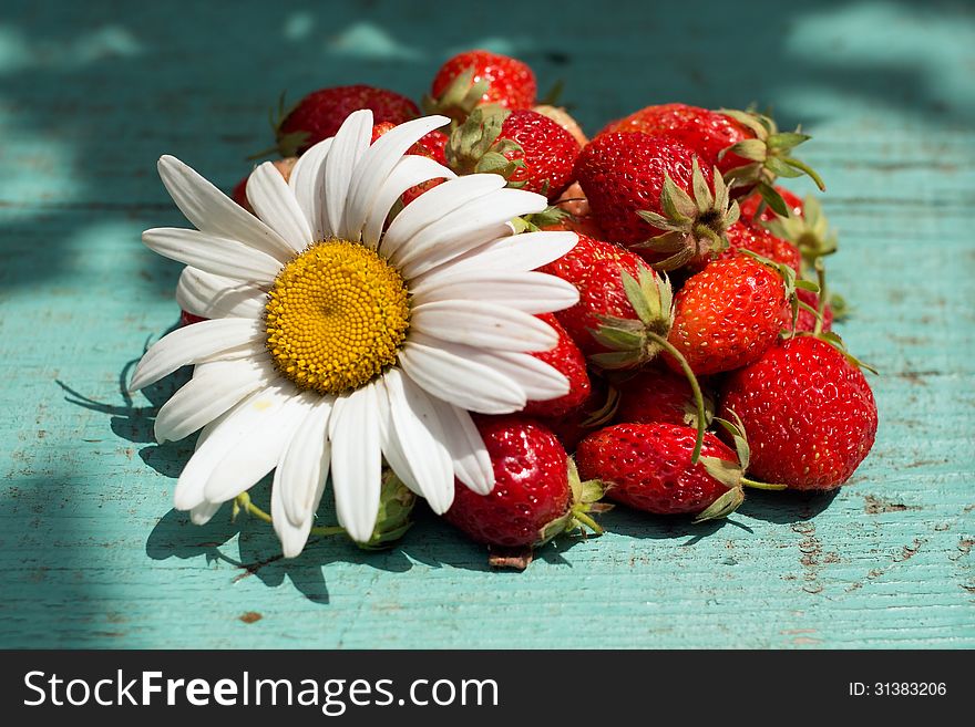 Сomposition of strawberries and chamomile on a wooden surface. Сomposition of strawberries and chamomile on a wooden surface