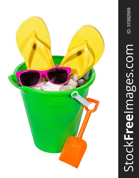 Vertical shot of a sand pail with sand, rocks, flip flops and sunglasses. Isolated on a white background. Vertical shot of a sand pail with sand, rocks, flip flops and sunglasses. Isolated on a white background.