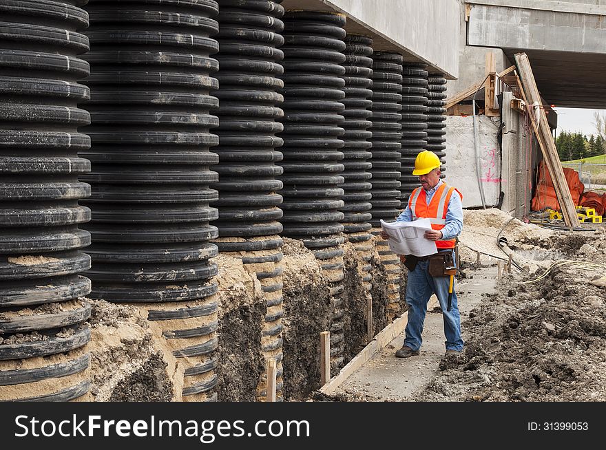 Bridge construction worker checking blueprint at job site