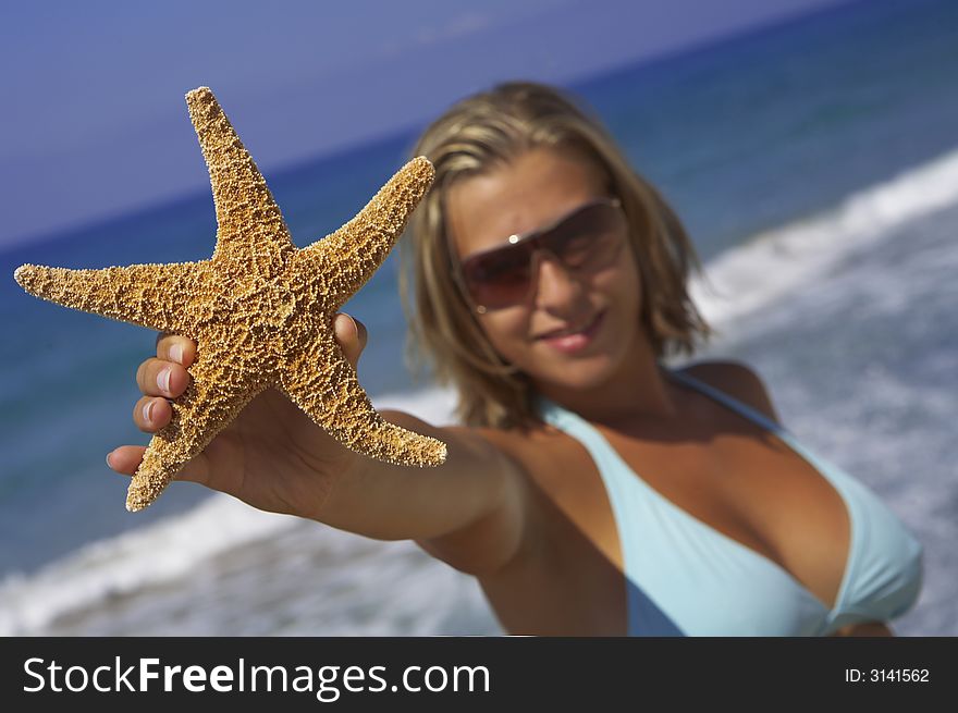 Young woman holding up a starfish in front of the beautiful ocean. Young woman holding up a starfish in front of the beautiful ocean