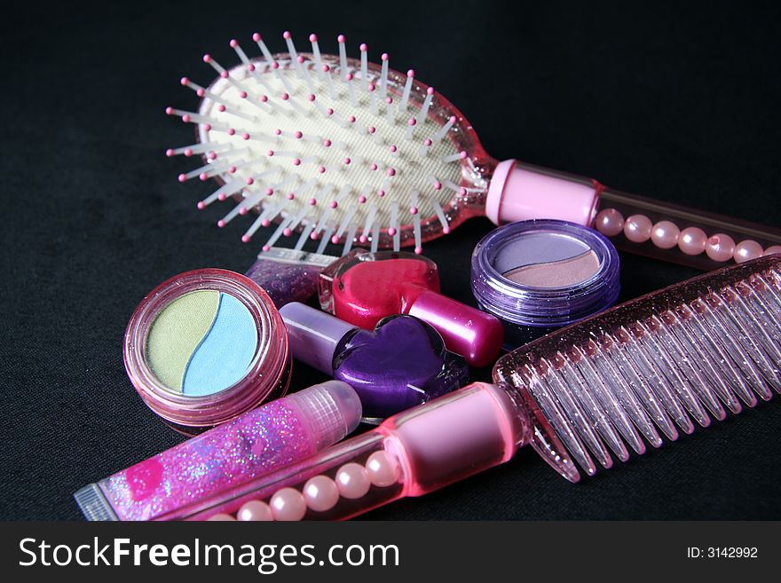 Cosmetics , comb and hair brush over black background