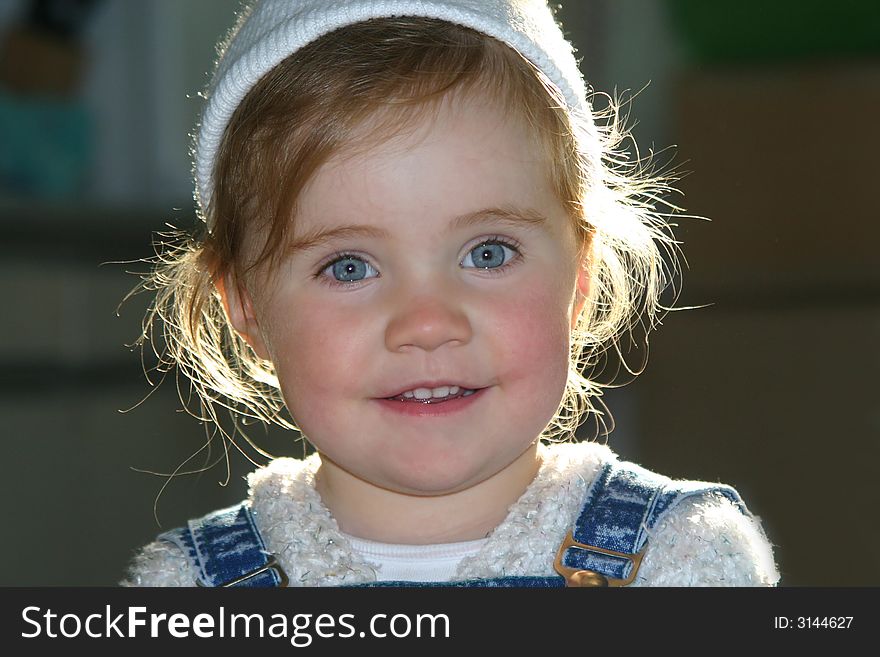 Smiley little girl in white hat over defocused background