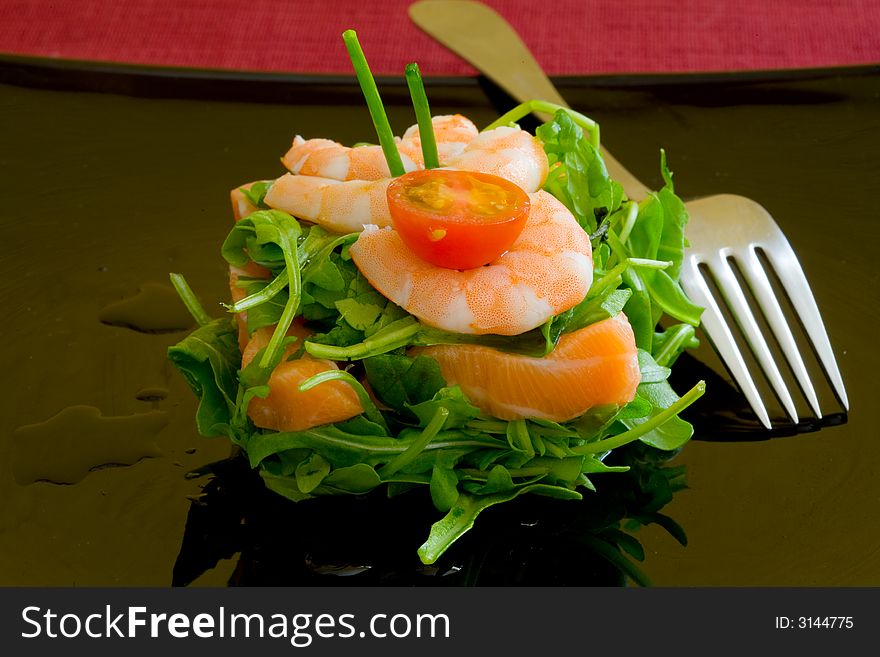 Fresh salmon tartar on black platter with rocket salad