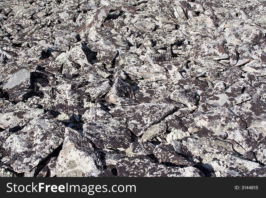 Lifeless rocky top of mountain with dry lichen over stones as a background