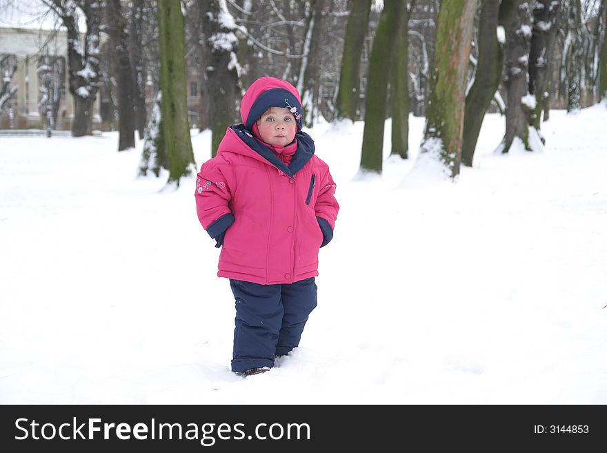 Little girl in winter clothes in snow park