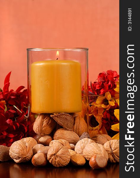 A single candle with nuts in autumn setting. A single candle with nuts in autumn setting