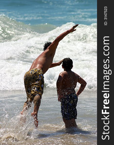 Young man jumping into the ocean in Malibu Beach, California