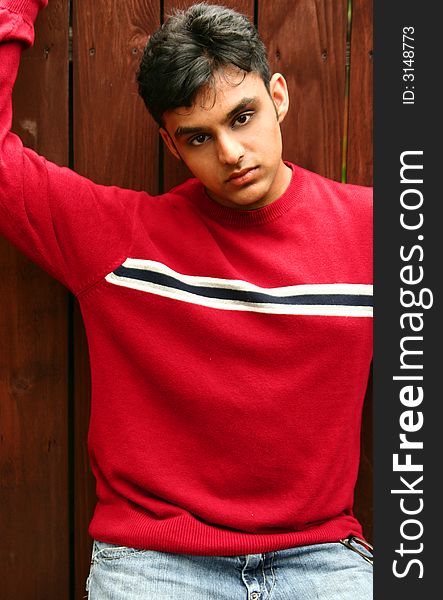 Fashion shoot of young indian man posing with wood background