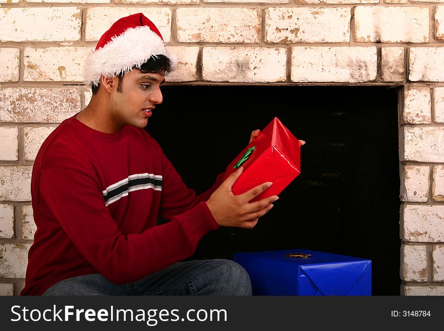 Young indian man wearing christmas hat holding present. Young indian man wearing christmas hat holding present