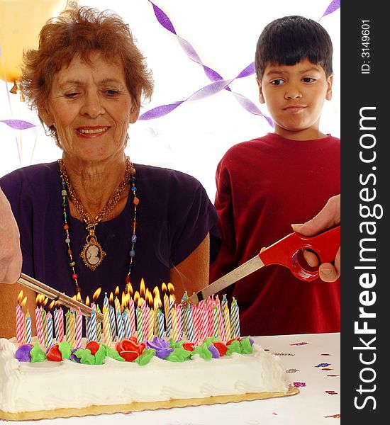 Two hands light the candles on an eighty-year-old woman's cake white her great grandson looks on. Isolated on white. Two hands light the candles on an eighty-year-old woman's cake white her great grandson looks on. Isolated on white.