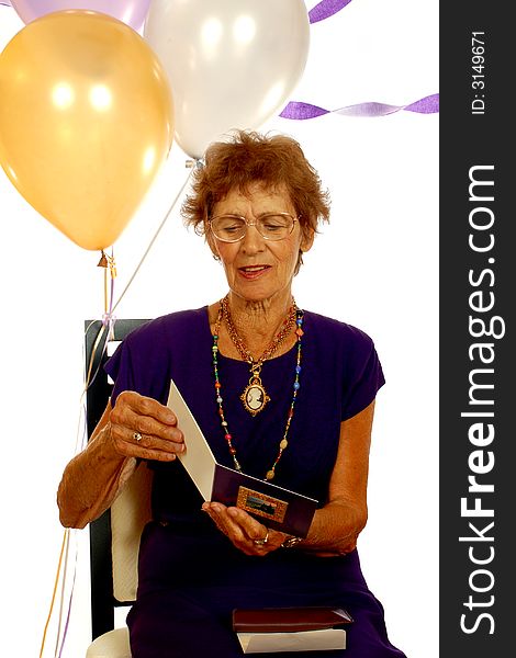 An eighty-year-old reading a card at her birthday party.  Isolated on white. An eighty-year-old reading a card at her birthday party.  Isolated on white.