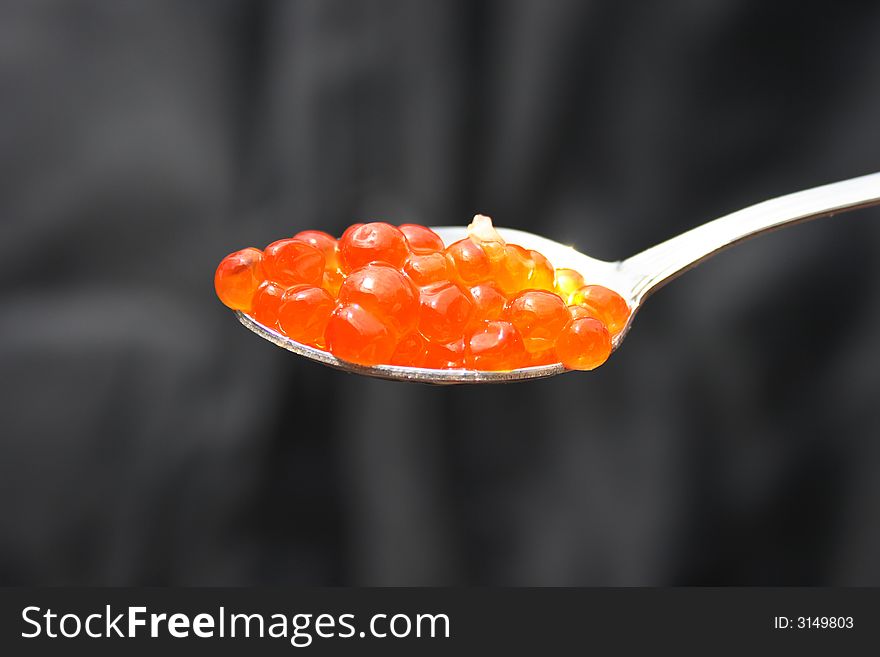 On a photo caviar in the spoon on a black background