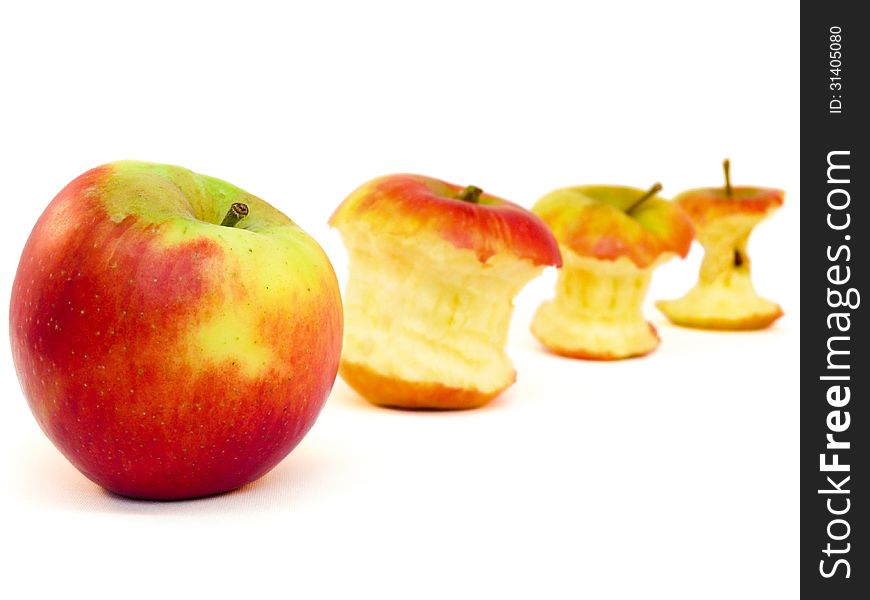 Four apples and apple cores lying diagonally on white. Four apples and apple cores lying diagonally on white