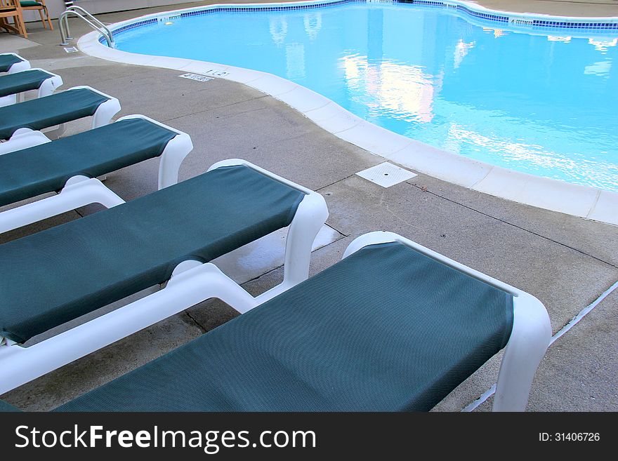 Deep blue lounge chairs set near the pool side,inviting swimmers to relax after their laps in the water. Deep blue lounge chairs set near the pool side,inviting swimmers to relax after their laps in the water.