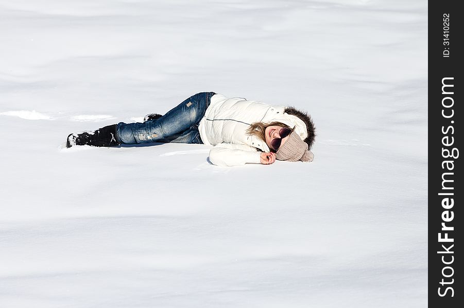 Young woman lying in snow enjoying a sunny winter day. Young woman lying in snow enjoying a sunny winter day