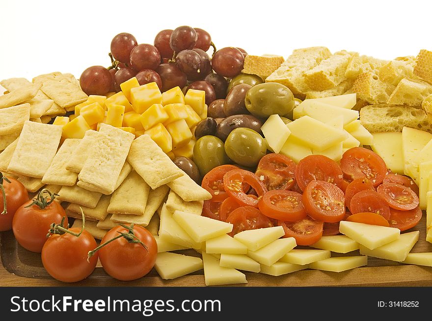 A selection of cheeses on a wooden board with olives, grapes and tomatoes. A selection of cheeses on a wooden board with olives, grapes and tomatoes.