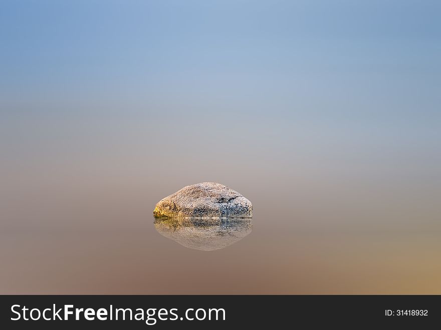 Abstract image with motion blurred sea, sky and stone