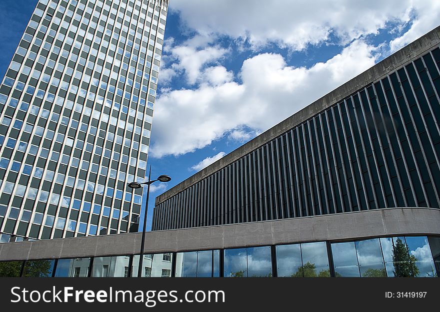 Skyscraper with surrounding buildings and blue sky with white clouds. Skyscraper with surrounding buildings and blue sky with white clouds