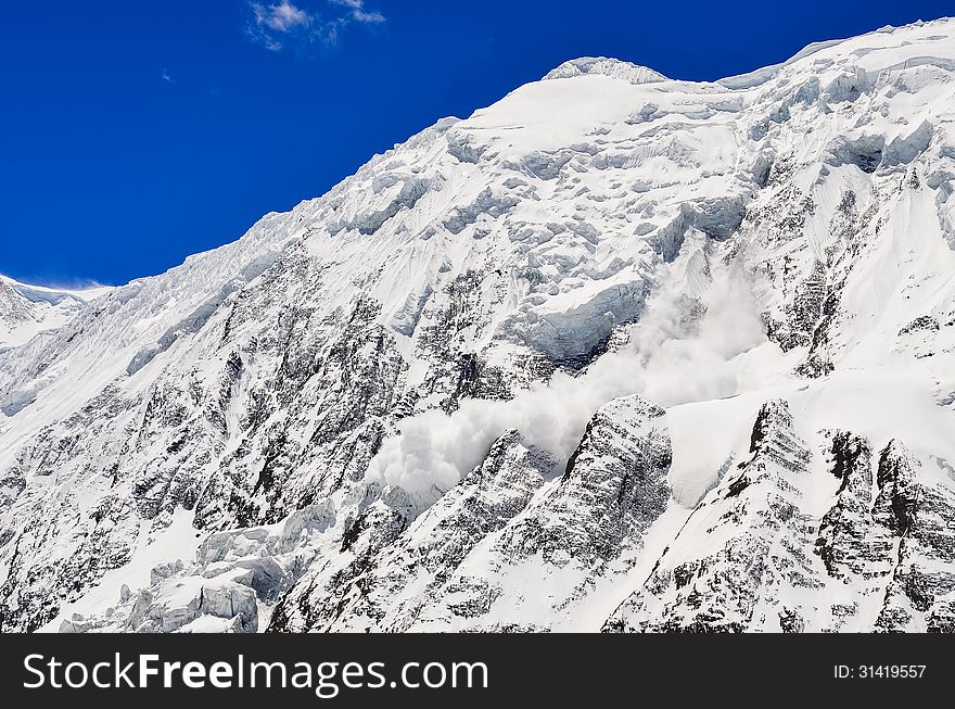 Avalanche falling from snowy frozen mountain peak